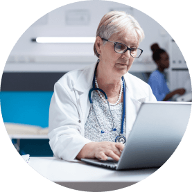 A healthcare professional typing on a laptop computer